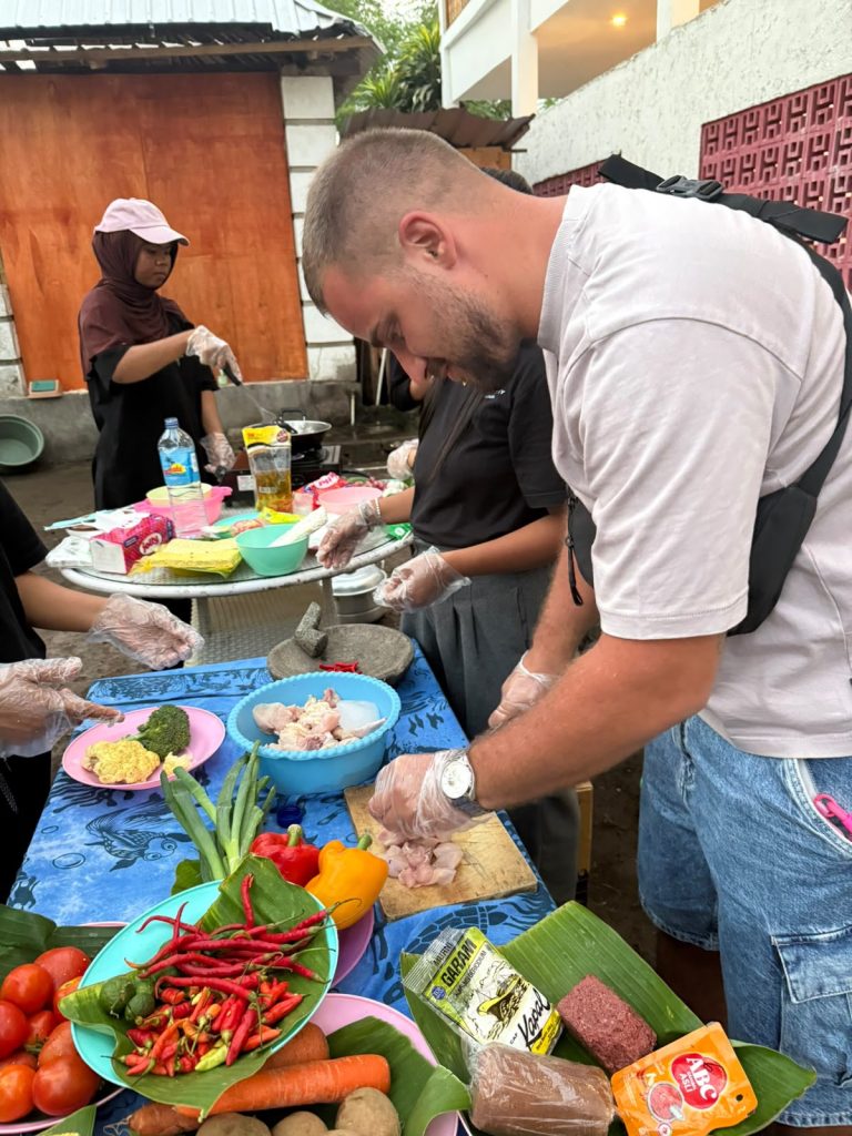 Fresh chillies, tomatoes and vegetables on a banana leaf while a guest chops