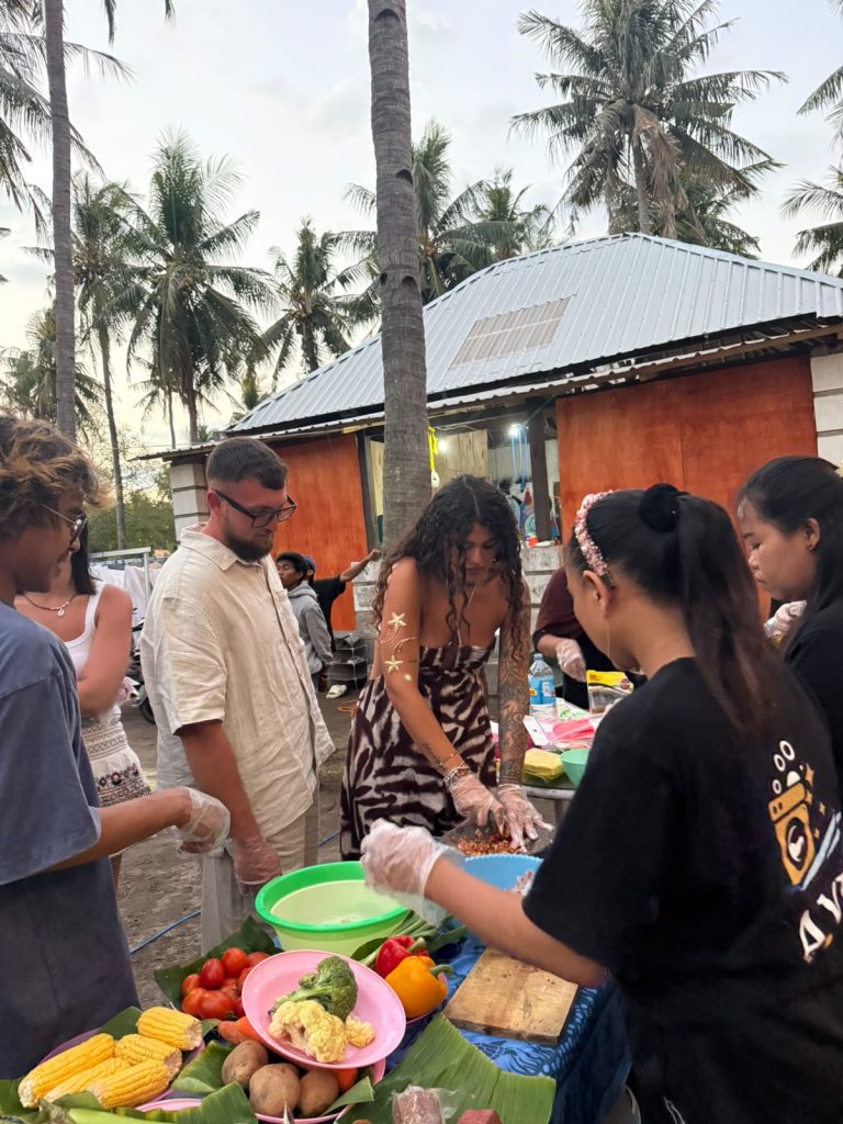 Guests and hosts preparing food outside the family home at dusk on Gili Trawangan