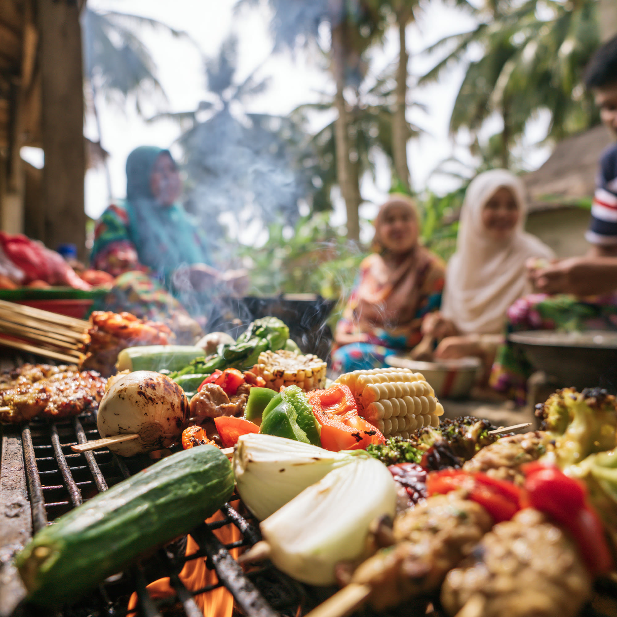 Satay skewers, corn and vegetables grilling over coals